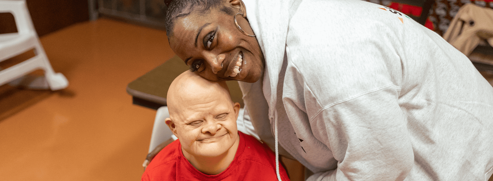 Two people smiling at the camera, head to head