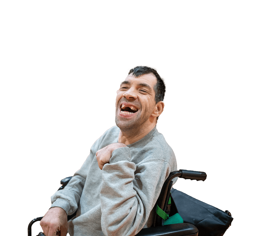 A man in a blue crewneck in a wheelchair, smiling