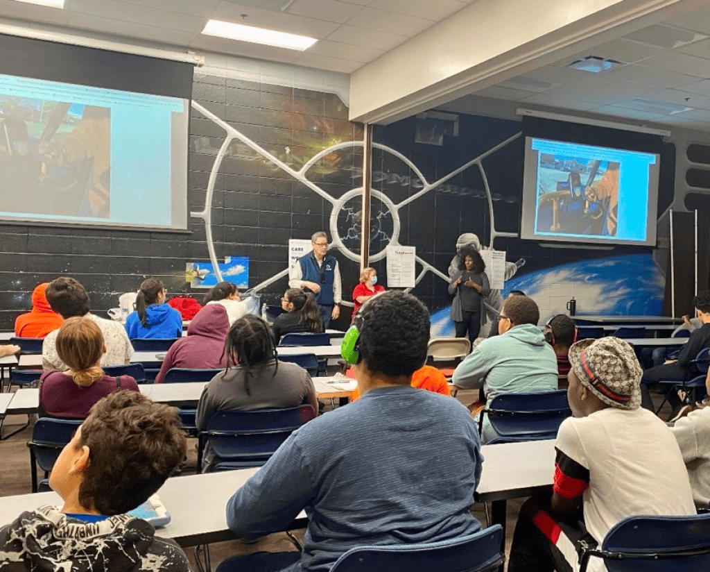 A man and two women presenting to a classroom of people