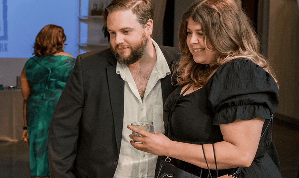 A man and a woman in black-tie attire looking off of the picture