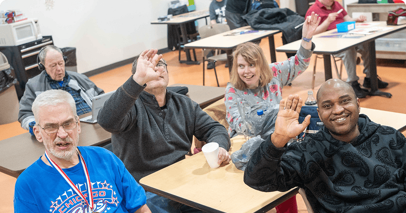 Group of people smiling and waving at the camera