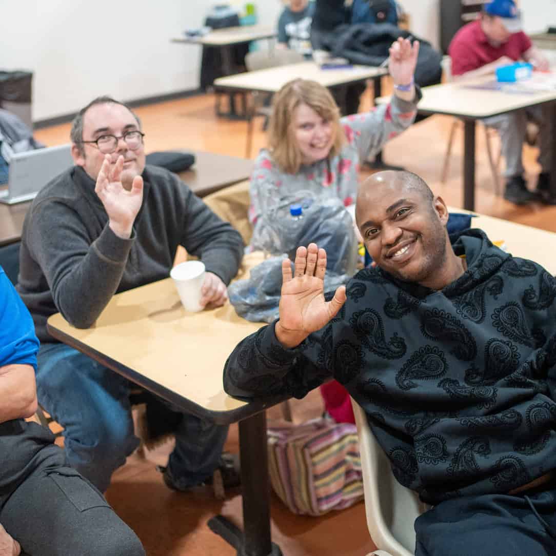 Group of people smiling and waving at the camera