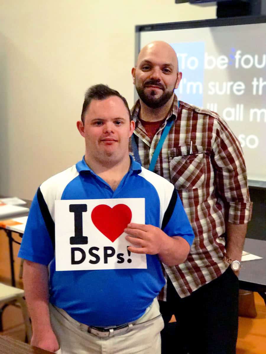Two men, one holding an "I Heart DSPs" sign