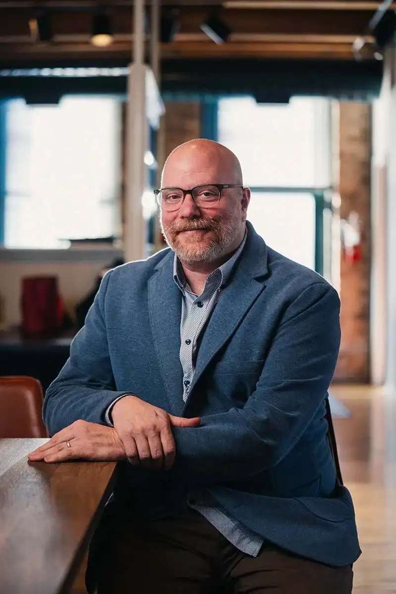 Portrait of Greg Petersen sitting at a table in a suit