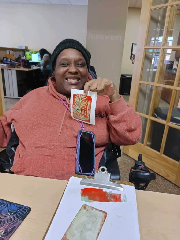 A woman holding up her artwork