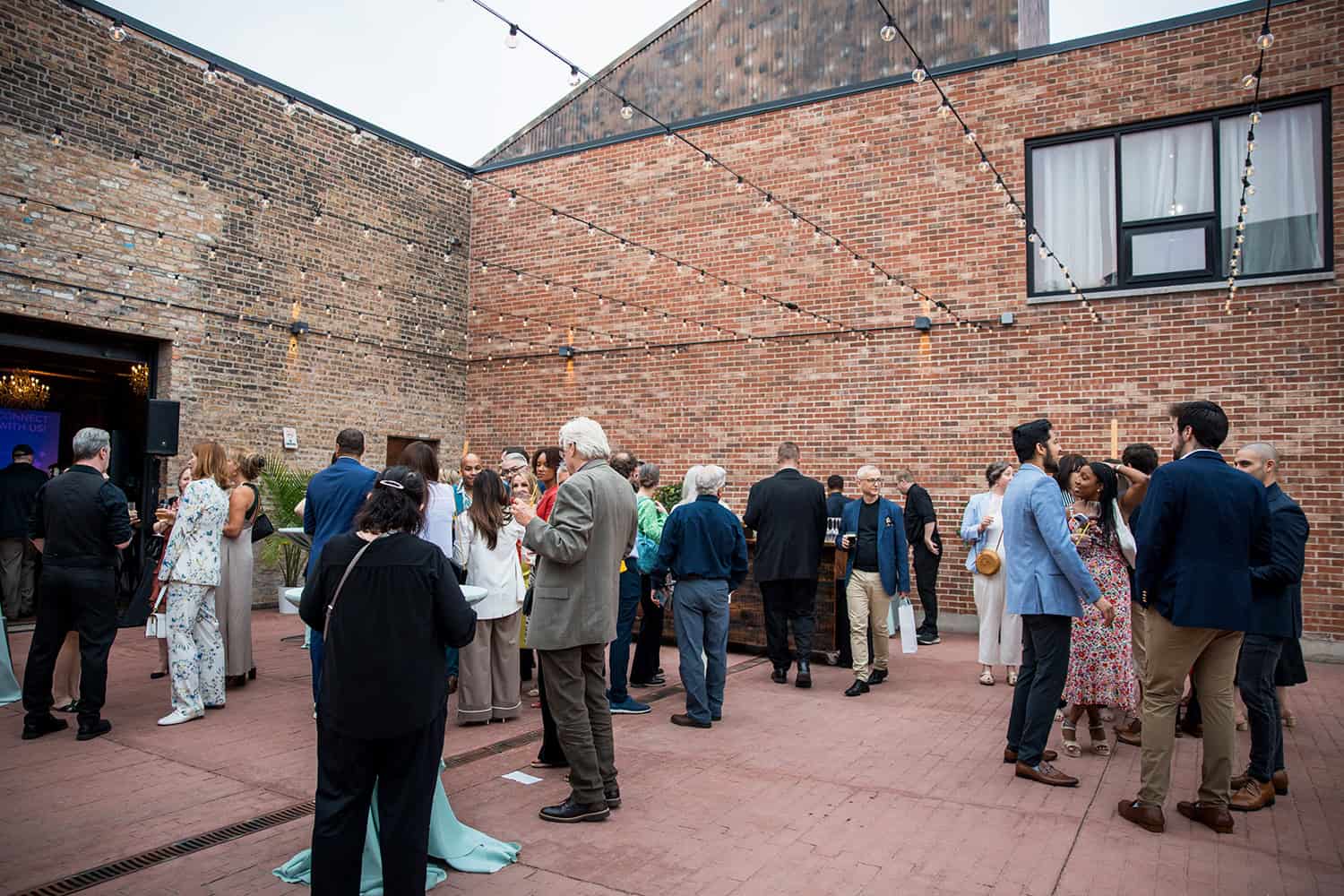 A gala event at a brick building with string lights over the patio