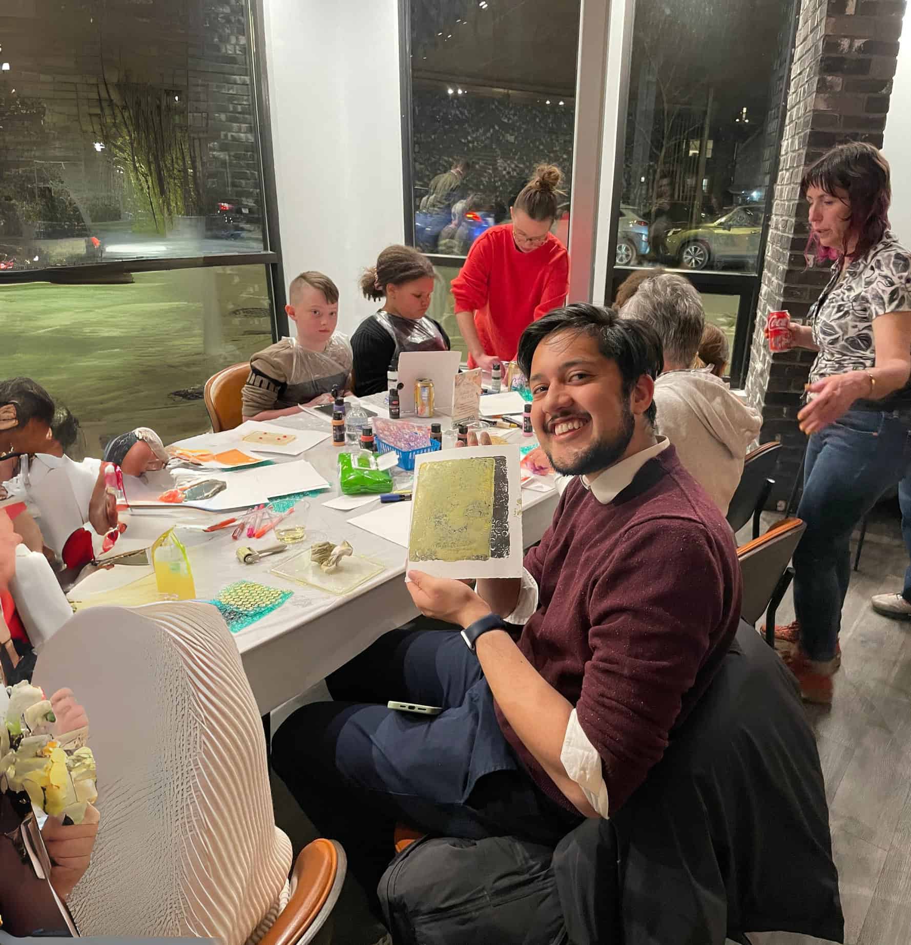 A man at an event holding up his artwork
