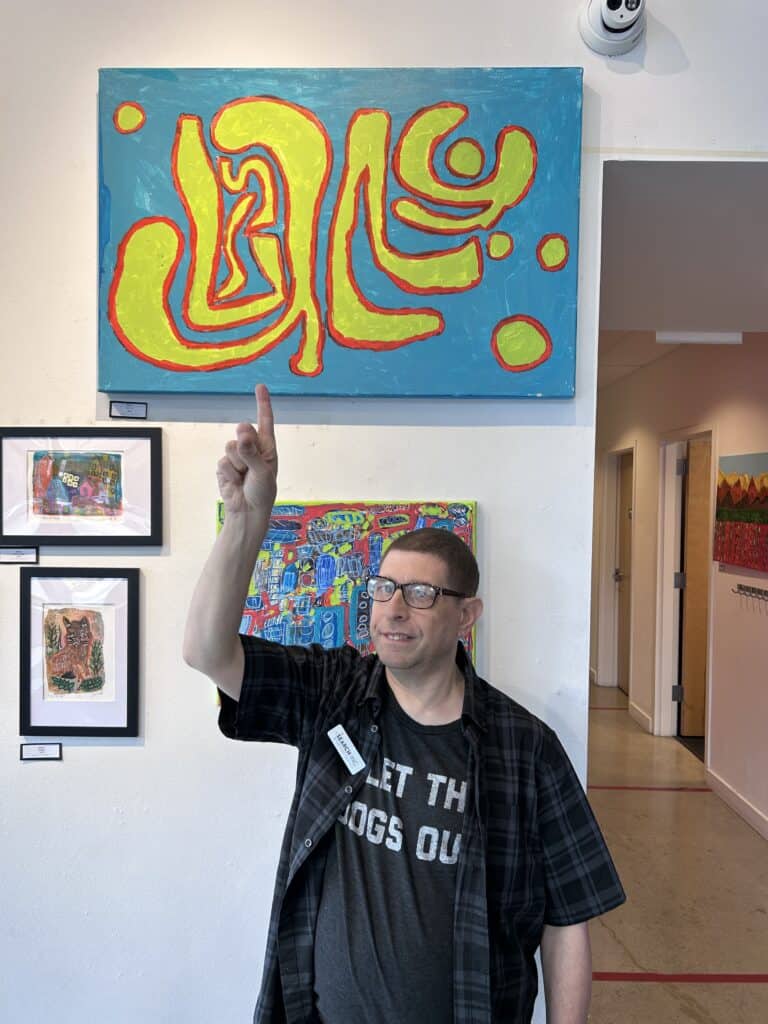 artist pointing out painting on gallery wall